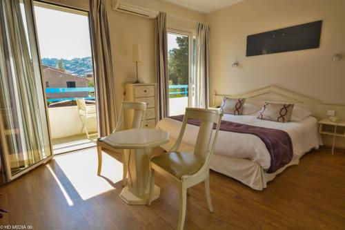 a bedroom with a bed and a table and chairs at Hôtel Méditerranée in Le Lavandou