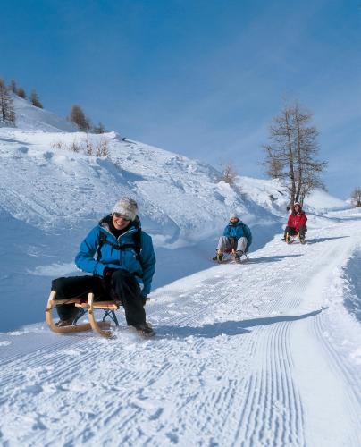 three people sitting on a sled in the snow at Haus Zer Trächu in Saas-Almagell