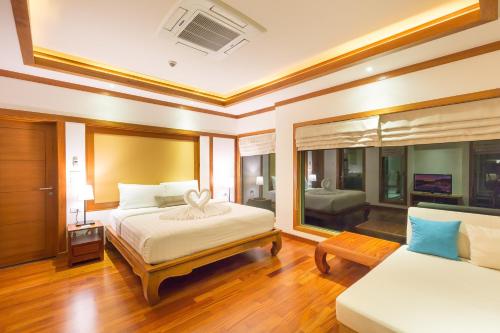 a large bedroom with a bed and a couch at Villa Tantawan Resort - Private Pool Villas in Kamala Beach