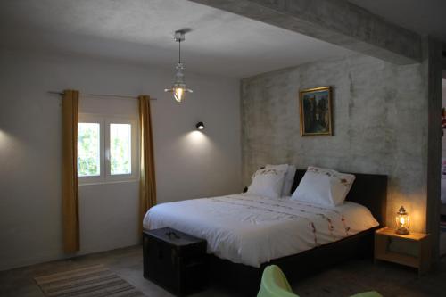 um quarto com uma cama com lençóis brancos e uma janela em Casa do Loureiro Branco em Santarém