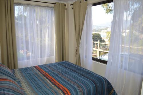 a bedroom with a bed and two large windows at Piedra Negra in Papudo