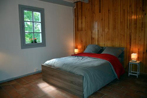 een slaapkamer met een bed met een houten muur bij La Maison Ratabou in Sainte-Eulalie-en-Born