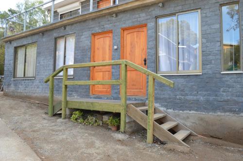a house with orange doors and a wooden staircase at Piedra Negra in Papudo