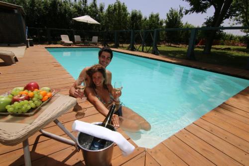 um homem e uma mulher sentados numa piscina com copos de vinho em Vitrage Holiday Village and Spa em Beit Hillel