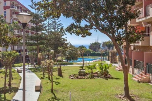 Un parque con árboles y una farola al lado de un edificio. en Apartamento Minerva Jupiter. The perfect accommodation for your vacation, en Benalmádena