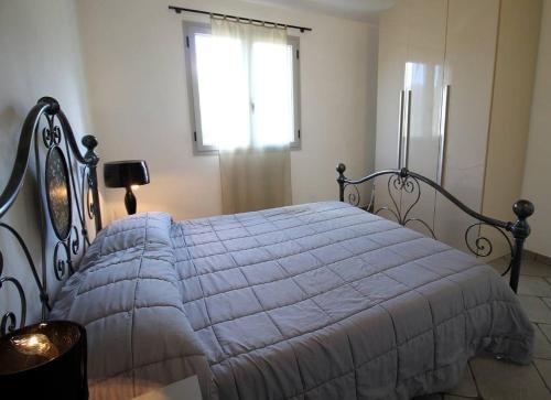 sypialnia z łóżkiem z kołdrą i oknem w obiekcie Casa vacanze gli ulivi w mieście Borgomaro