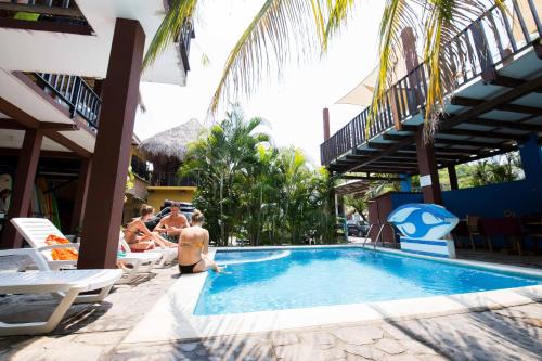 um grupo de pessoas sentadas ao redor de uma piscina em Papaya Lodge em La Libertad