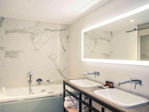 une salle de bain avec un lavabo, une baignoire et un miroir dans l'établissement Mercure Périgueux Centre Historique, à Périgueux