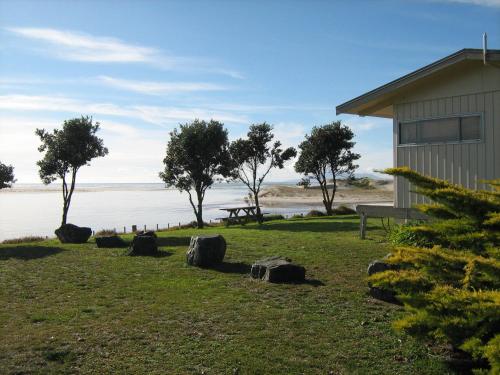 a building next to a body of water with trees at Pakiri Beach Holiday Park in Pakiri