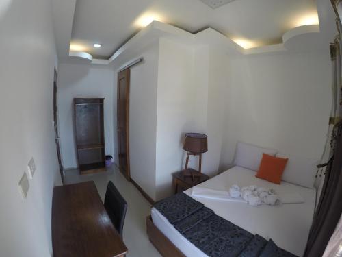 a small room with a bed and a table and a desk at El Nido Royal Palm Inn in El Nido