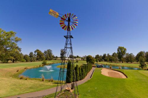 a windmill on a golf course with a pond at Howlong Golf Resort in Howlong