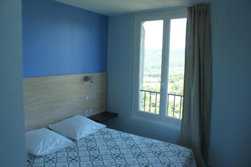 a bedroom with a bed and a large window at Hotel le Belvédère in Moustiers-Sainte-Marie