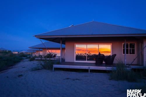 a person sitting on a bench in front of a house at Eco Beach Wilderness Retreat in Broome