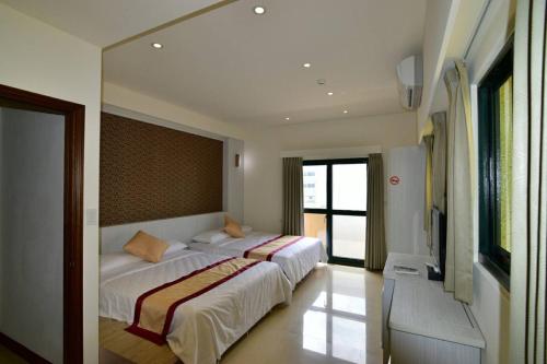 a bedroom with two beds and a large mirror at Penghu Luna Sea Homestay in Magong