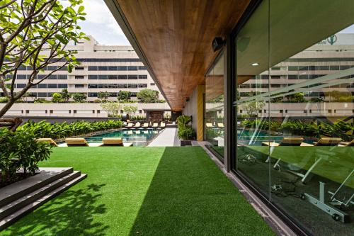 an external view of a building with a pool and grass at Best Western Premier Sukhumvit in Bangkok