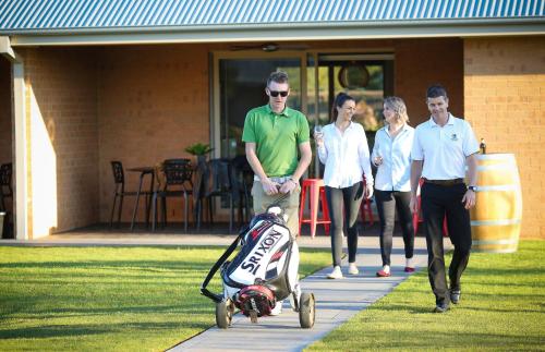 a man pushing a stroller on a sidewalk with people at Howlong Golf Resort in Howlong