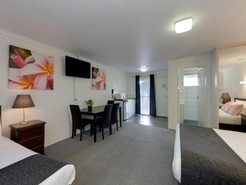 a room with a bed, table, chairs and a television at Frankston Motel in Frankston