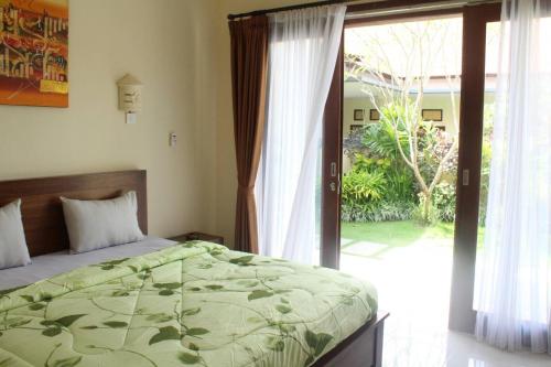 a bedroom with a bed and a sliding glass door at Purnama Guesthouse in Canggu