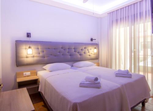 a bedroom with a large white bed with towels on it at Ntinas Filoxenia Hotel & Spa in Skala Potamias