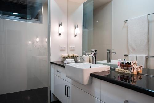 a white bathroom with a sink and a mirror at Azura in Daylesford