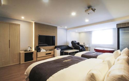 a hotel room with two beds and a flat screen tv at No.1 New Yorker Hotel in Jinju