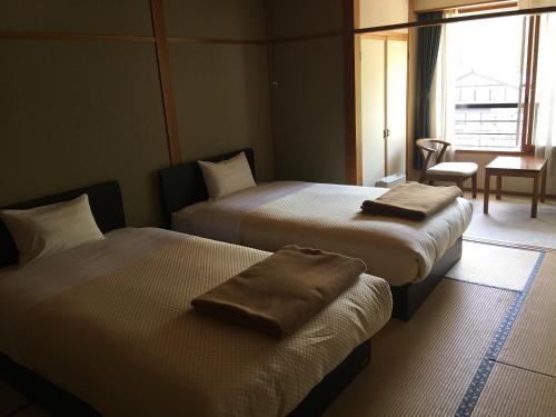 a hotel room with two beds with towels on them at Hotel Hirayunomori Annex in Takayama