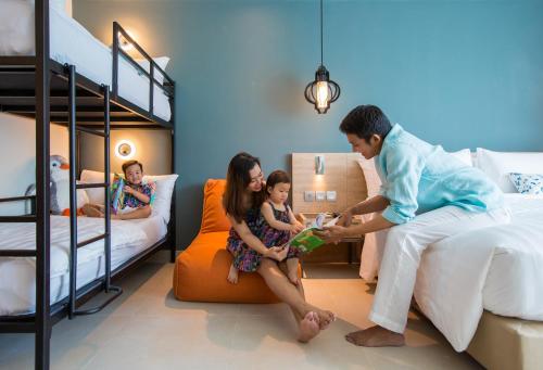 a family sitting in a bedroom with bunk beds at Fusion Suites Phuket Patong in Patong Beach