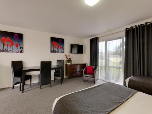a hotel room with a bed and a table and chairs at Frankston Motel in Frankston