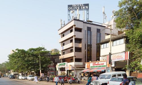 een drukke stadsstraat met een gebouw met een bord erop bij Treebo Trend Olive Inn in Mumbai
