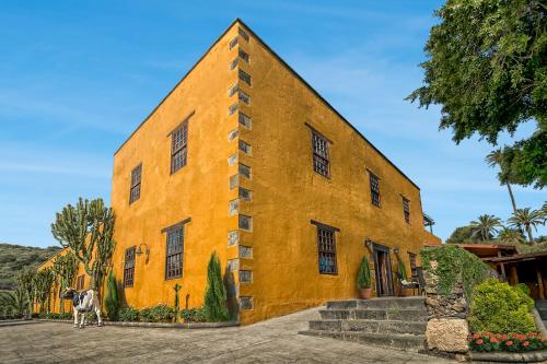 uma vaca em pé em frente a um edifício amarelo em Hotel Rural LIVVO Maipez em Las Palmas de Gran Canárias