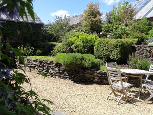 a table and chairs in a garden with a stone wall at Le Héron in Houffalize