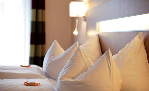 a white bed with white pillows and a red object on it at Hohenzollern in Bad Neuenahr-Ahrweiler