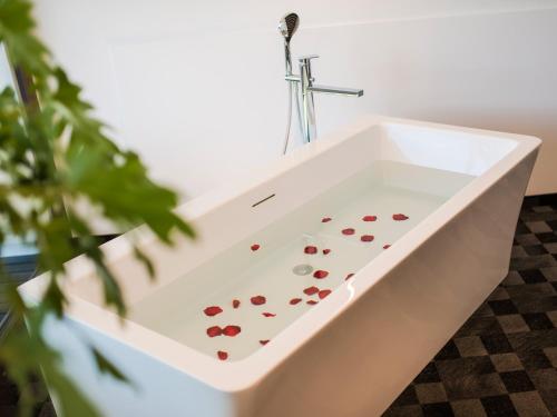 a white bath tub with red hearts in it at Garni Hotel Katzenthalerhof in Lana
