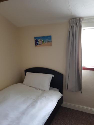 a bedroom with a white bed with a window at Oak Cottage in Burgh le Marsh