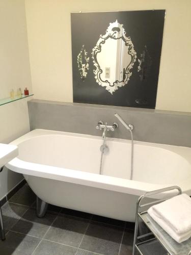 une baignoire blanche dans une salle de bain avec un miroir dans l'établissement Port rive gauche Gabian, à Marseillan