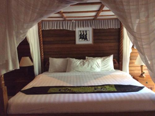 a bedroom with a bed with a white comforter at Sunset Villa Lembongan in Nusa Lembongan