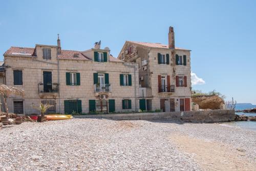 a large stone house on the shore of a beach at Apartments On the Beach in Komiža