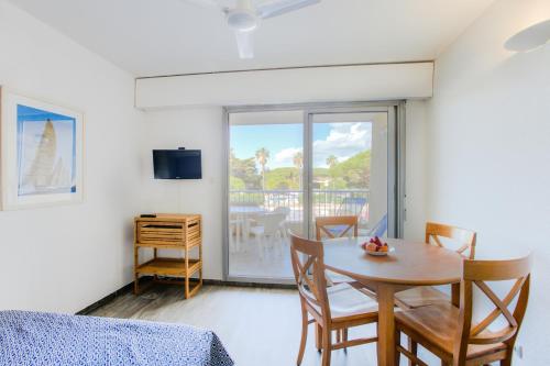 un salon avec une table, des chaises et une télévision dans l'établissement Residence Hyeres Parc - maeva Home, à Hyères
