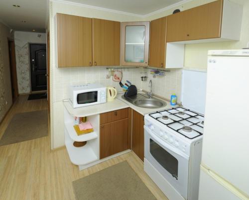 オムスクにあるOmsk Sutki Apartments on Irtyshskaya Naberezhnaya 12のキッチン(白いコンロ、電子レンジ付)