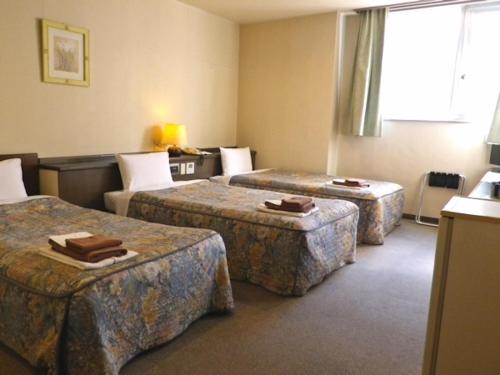 um quarto de hotel com três camas e um sofá em Isesaki Harvest Hotel em Isesaki