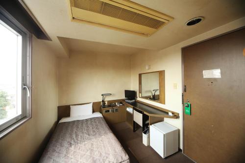 Isesaki Harvest Hotel في Isesaki: غرفة صغيرة بها سرير ومغسلة