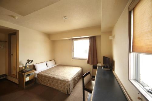 a hotel room with a bed and a window at Isesaki Harvest Hotel in Isesaki