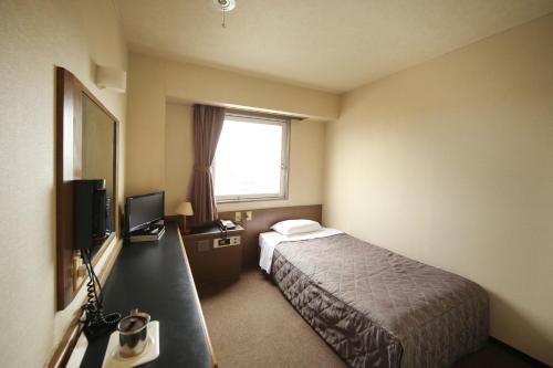 a hotel room with a bed and a window at Isesaki Harvest Hotel in Isesaki