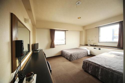 a hotel room with two beds and a flat screen tv at Isesaki Harvest Hotel in Isesaki