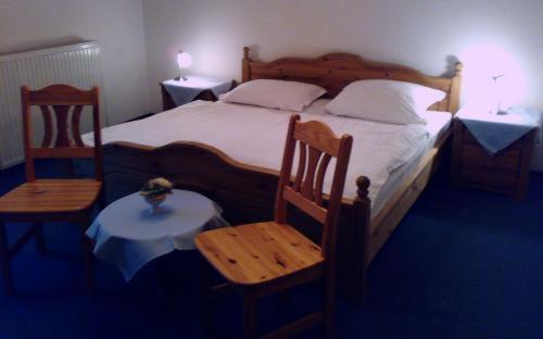 a bedroom with a bed with two chairs and a table at Hotel Royal Garden in Bad Iburg