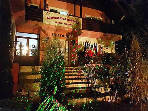 a building with a christmas tree in front of it at Pensiunea Agroturistică Piscul Soarelui in Cîmpulung