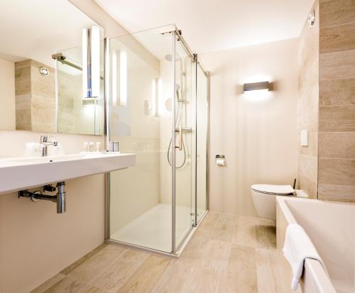 ein Bad mit einer Dusche, einem Waschbecken und einem WC in der Unterkunft WestCord Hotel Schylge in West-Terschelling
