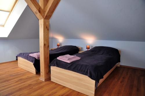 two twin beds in a room with wooden floors at Modrzewiowe Wzgorze in Promno