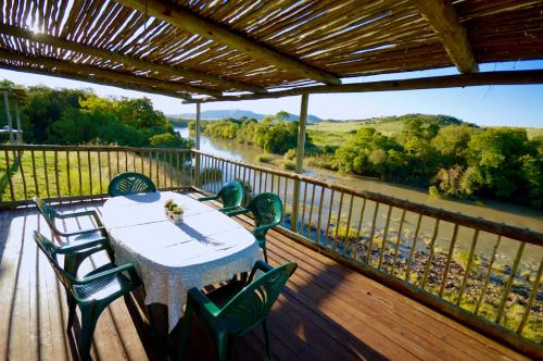 una mesa y sillas en una terraza con vistas al río en Swartkop Cottage, en Winterton