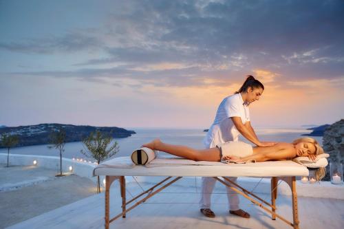 a woman getting a massage from a woman sitting on a table at Thermes Luxury Villas And Spa in Megalokhori